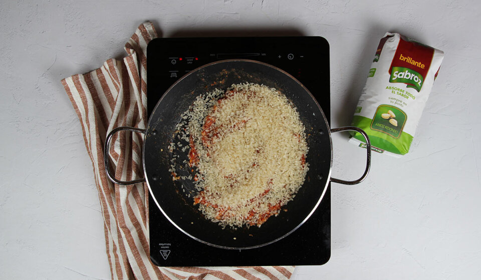 Añadir arroz a paella de calamares