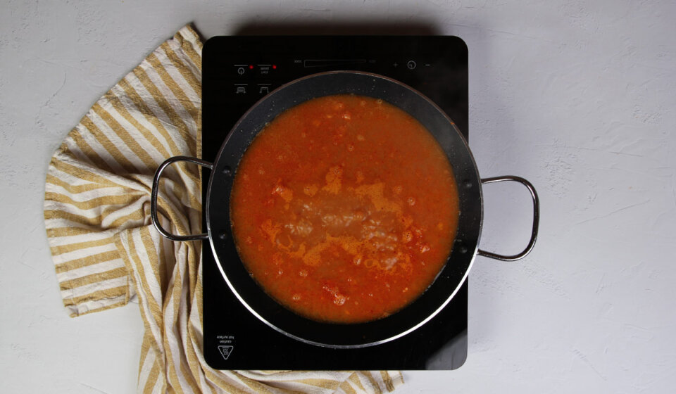 Añadir caldo a paella de pescado