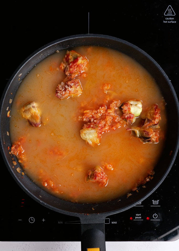 Incorporar caldo a Arroz con alcachofas y habas