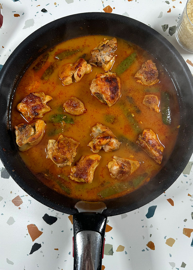 Verter caldo en paella de pollo y conejo